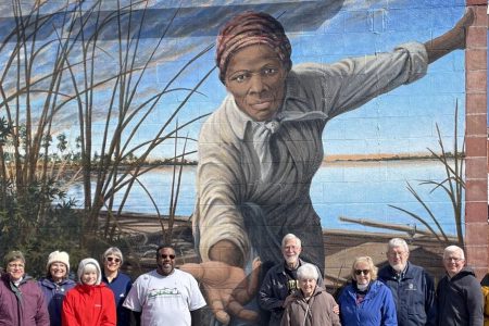 The pilgrims stand before the Harriet Tubman Mural on an exterior wall of the Harriet Tubman Museum and Educational Center in Cambridge, Maryland. Artist Michael Rosato designed and painted the mural, which was completed in 2019. From left to right: Paul Knapke, JoAnn Knapke, Julie Hart, Rachel Gratz, Krisann Applegate, Alex Green (Harriett Tubman Tours tour guide), Philip Hart, Katherine Bauman, Marlene Suter, Scott Applegate, Conrad Gratz. Photo by Arloa Bontrager.