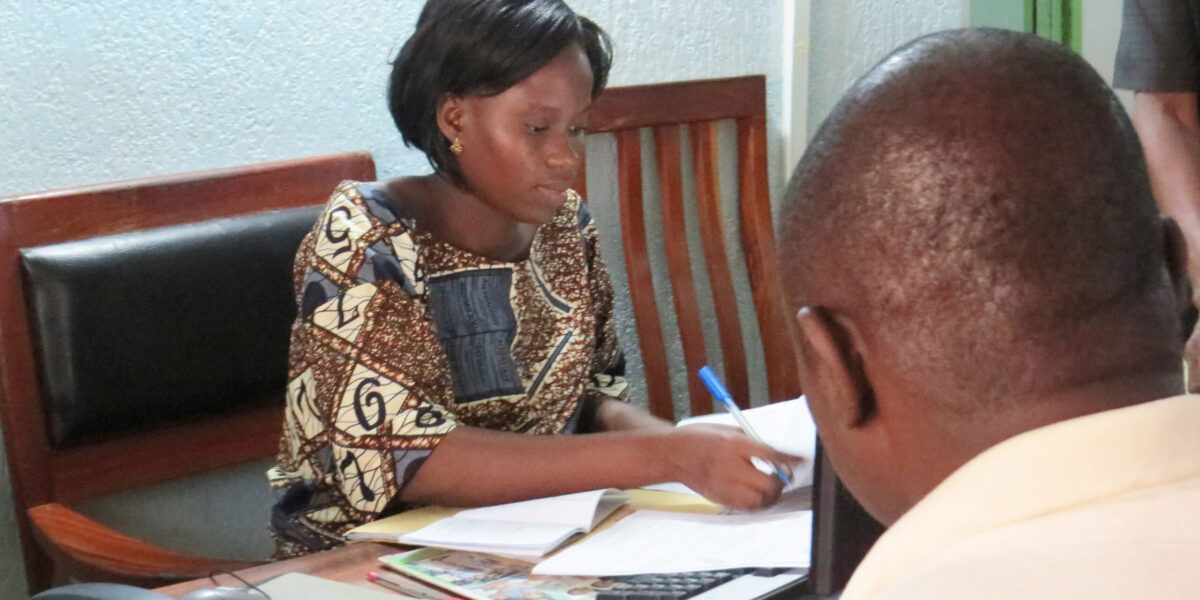 Liduine Tokoudagba helps a PEBCo client open an account. Photo by Lynda Hollinger-Janzen. Download full-resolution image.