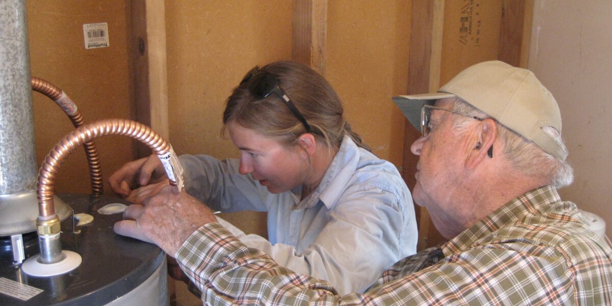Walter Good and Miriam Regier work together to repair a water heater