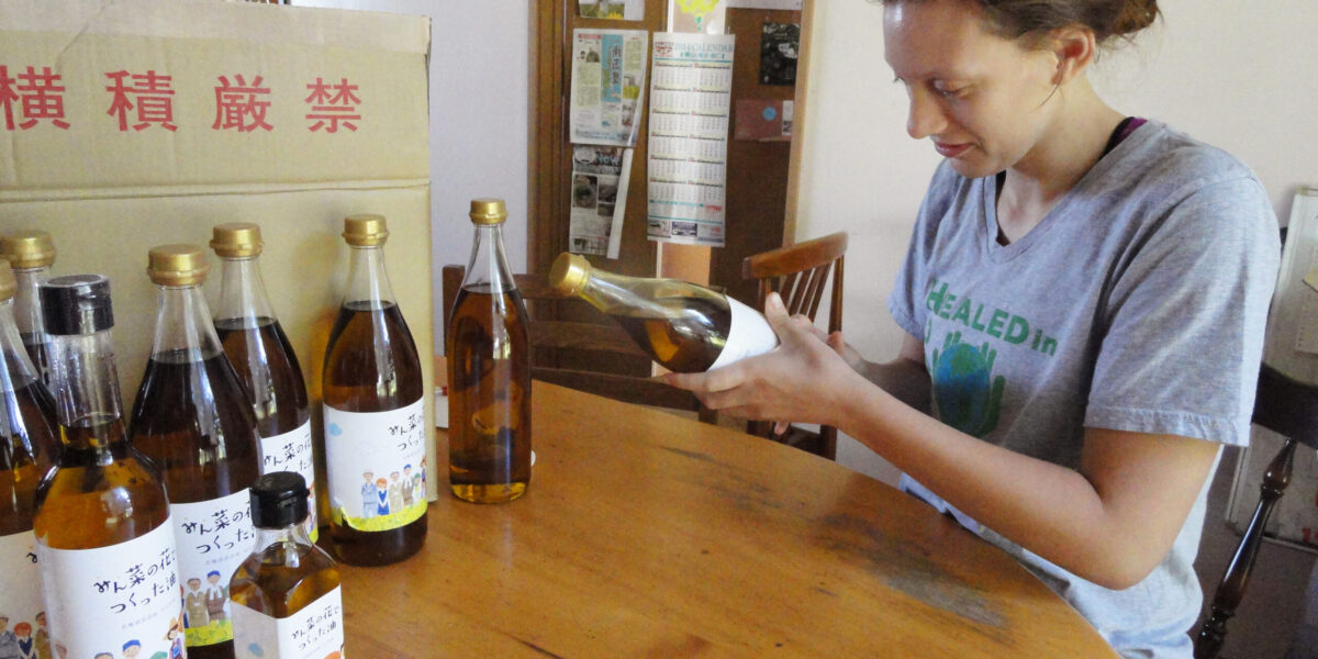 Tierney Frey attaches labels to the bottles of canola oil produced by Menno Village during Youth Venture Japan this summer. Photo by Abby Findley. Download full resolution image.