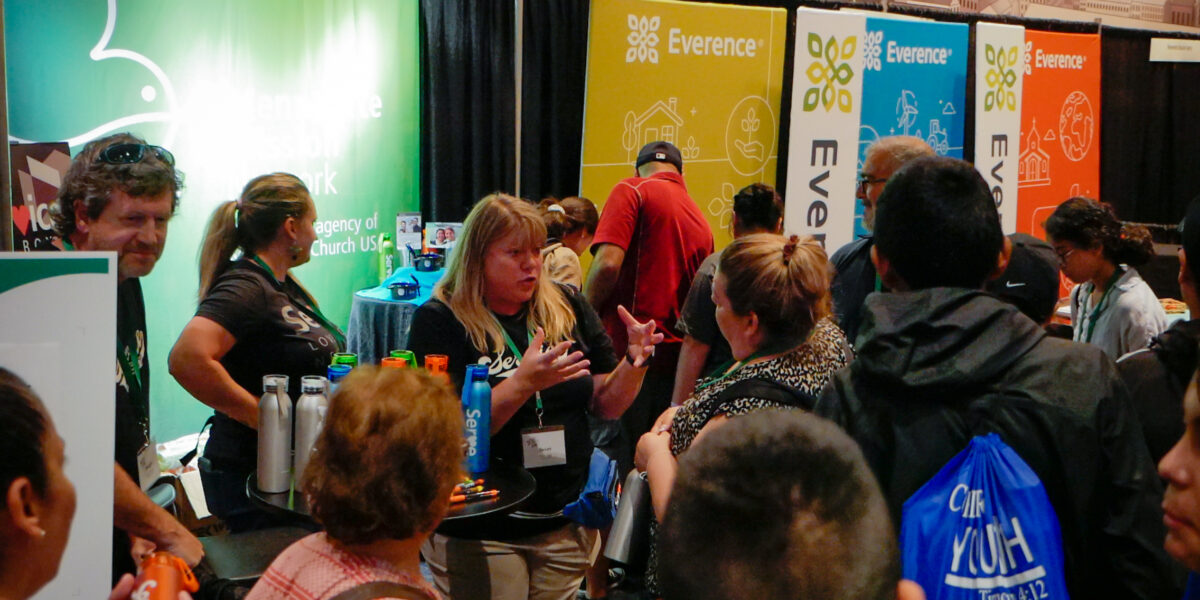 Susan Nisly (center) talks with visitors at the MMN booth on Tuesday