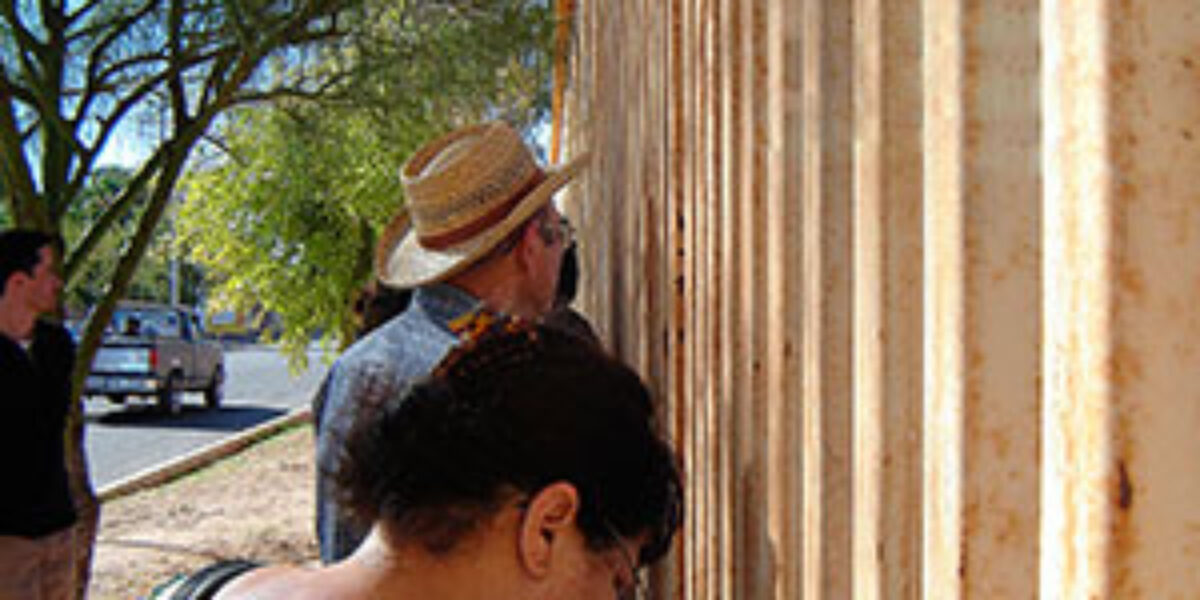 Members of a tour to the Mexico-United States border pray at the wall dividing the two countries.