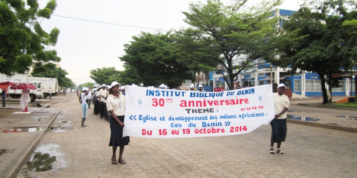 Solange Akpo and Delphine Worou lead the Benin Bible Institute procession through the streets of Cotonou to the rhythms of a brass band