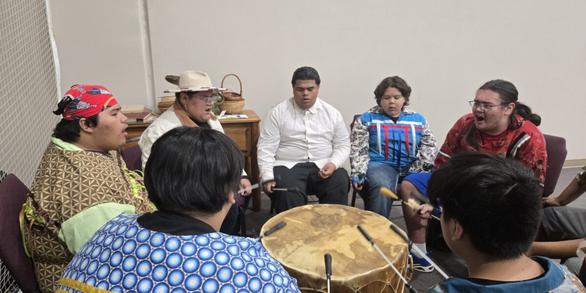 Dewy Bill, third from left, leads the Mending Wings singers and drummers. Photographer: Sarah Augustine.