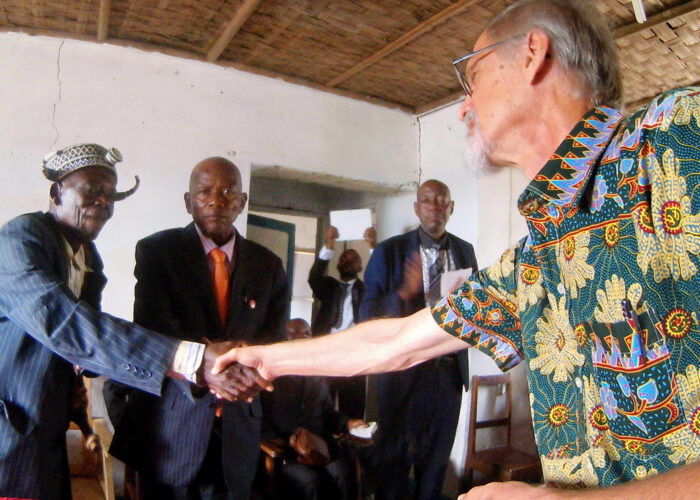 One of the traditional dignitaries from the surrounding region shakes Rod Hollinger-Janzen's hand during the ceremony of confession and reconciliation in Kandale