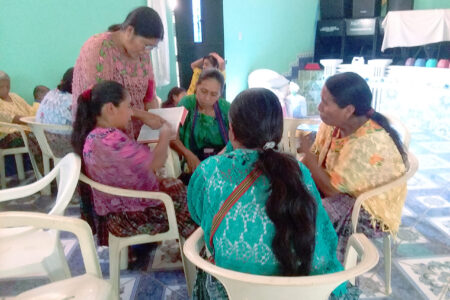​Kekchi leader Julia Xol (standing) helps four Kekchi leaders at Nuevo Chintun Mennonite Church in the Tucuru region in Guatemala to study a biblical text on the Holy Spirit. The leaders pictured here will then present the material at a Bible study day for Kekchi women at one of the Kekchi Mennonite churches. Photo by Deb Byler. 