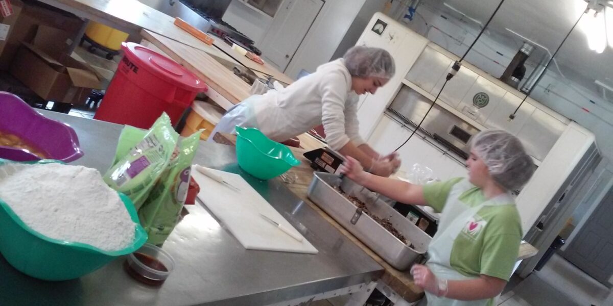 ​Alina and Marta Bergstresser help mix batter for date-nut bread in the Koinonia Farm bakery during their SOOP term in April 2019 in Americus