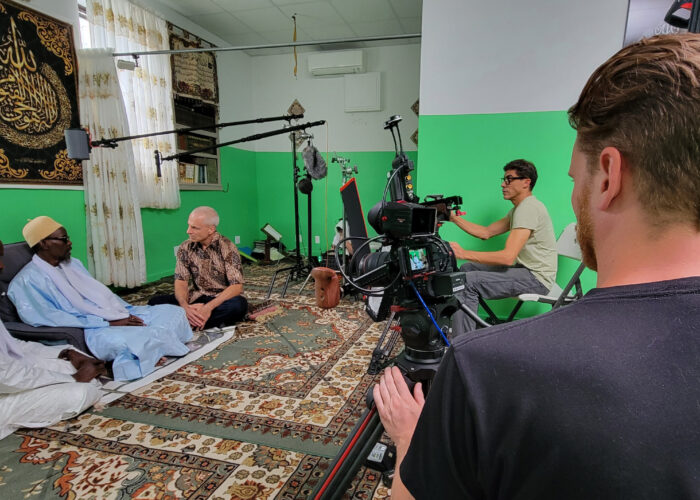 Naylul Maraam Islamic Center is a Quranic school in Harlem, founded and led by Ustaz Abdou Mbaye (far left). Jonathan Bornman is interviewing Serigne Afia Niang. Director of Photography Ehab Assal is seated at camera and crew member Josh Feezer is standing, on the second camera. Photo by D. Michael Hostetler.