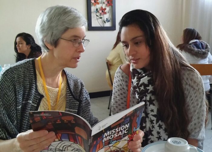 At a Sister Care seminar in 2017, Linda Shelly shares with Cielo Arguello the inclusion of her ministry in Iquitos, Peru, in the Mennonite Mis­sion Network prayer directory. Photo by Rhoda Keener.