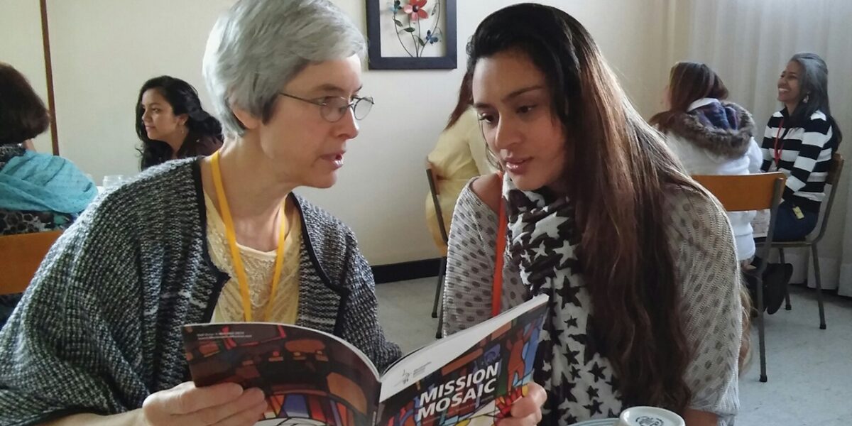 At a Sister Care seminar in 2017, Linda Shelly shares with Cielo Arguello the inclusion of her ministry in Iquitos, Peru, in the Mennonite Mis­sion Network prayer directory. Photo by Rhoda Keener.